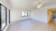Located at 100 SW 14th St in Boca Raton, FL, this clean and contemporary 3-bedroom, 2-bathroom unit offers a well-designed single-floor layout with a bright, modern aesthetic. Light wood-style flooring runs throughout the space, complementing the crisp white walls and creating a cohesive, airy feel.

The open-concept kitchen and living area serves as the heart of the home. The kitchen is outfitted with high-gloss white cabinetry, stainless steel appliances including a refrigerator, range, microwave, and dishwasher, and a large white island that provides both prep space and casual seating. Recessed lighting and a side window keep the kitchen well-lit and bright.

The living area features large black-framed windows and a glass-panel entry door that frame views of the surrounding greenery and neighborhood, flooding the space with natural light. A ceiling fan adds comfort to this open space.

Each of the three bedrooms continues the light wood flooring and white walls, with black-framed windows offering views of lush outdoor vegetation. The spacious primary bedroom includes closet space and a ceiling-mounted light fixture. The two bathrooms are finished with striking floor-to-ceiling marble-look tile in the walk-in showers, adding an elegant, upscale touch to the overall design.