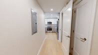 Located at 105 Washington St in Boston's Brighton neighborhood, this thoughtfully designed residence offers three bedrooms and three bathrooms across a single floor. Light hardwood flooring runs throughout, creating a cohesive and bright aesthetic in every room. The combined kitchen and living area serves as the heart of the home, featuring a modern kitchen outfitted with high-gloss white upper cabinetry, gray lower cabinets, a subtle tile backsplash, quartz countertops, and a full suite of stainless steel appliances including a gas range, microwave, dishwasher, and refrigerator. The spacious primary bedroom is bathed in natural light through large windows with neighborhood views and includes an open closet with built-in shelving. Additional bedrooms offer warm wood flooring and clean neutral walls, each accessible via a central hallway. The bathrooms are notably refined: one features a glass-enclosed walk-in shower with striking marble-style porcelain tile in warm gold and white tones, while another includes a full soaking tub with tiled surround and polished stone flooring. Recessed lighting and crisp white trim throughout complete the clean, contemporary feel of this well-appointed Boston residence.