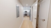 Located at 105 Washington St in Boston's Brighton neighborhood, this thoughtfully designed residence offers three bedrooms and three bathrooms across a single floor. Light hardwood flooring runs throughout, creating a cohesive and bright aesthetic in every room. The combined kitchen and living area serves as the heart of the home, featuring a modern kitchen outfitted with high-gloss white upper cabinetry, gray lower cabinets, a subtle tile backsplash, quartz countertops, and a full suite of stainless steel appliances including a gas range, microwave, dishwasher, and refrigerator. The spacious primary bedroom is bathed in natural light through large windows with neighborhood views and includes an open closet with built-in shelving. Additional bedrooms offer warm wood flooring and clean neutral walls, each accessible via a central hallway. The bathrooms are notably refined: one features a glass-enclosed walk-in shower with striking marble-style porcelain tile in warm gold and white tones, while another includes a full soaking tub with tiled surround and polished stone flooring. Recessed lighting and crisp white trim throughout complete the clean, contemporary feel of this well-appointed Boston residence.