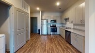Located in Douglasville, GA, this single-floor unit offers a clean, modern design throughout. The open-concept layout connects the main living area to a well-appointed kitchen, which features light wood-tone cabinetry, granite-style countertops, a full suite of stainless steel appliances including a refrigerator, electric range, microwave, and dishwasher, and durable wood-style plank flooring that extends through the main living spaces. Recessed lighting illuminates the kitchen and common areas, creating a bright and welcoming atmosphere. Multiple bedrooms are finished with soft wall-to-wall carpeting, ceiling fans, and windows with blinds that allow for natural light. The unit includes multiple bathrooms, one featuring a single-sink vanity with wood-tone cabinetry and a walk-in shower area, while another offers a bathtub-shower combination alongside a vanity and access to a walk-in closet with built-in shelving. Neutral wall tones and clean finishes throughout contribute to a cohesive and contemporary aesthetic. The layout, as visible from the dollhouse view, offers a functional and spacious floor plan well-suited for everyday living.