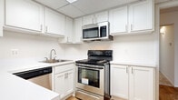 This single-floor residence in Southfield, Michigan offers a well-designed layout encompassing two bedrooms, two full bathrooms, and a versatile den. The open-concept flow is immediately apparent, with wood-style flooring in the entry and common areas transitioning to plush carpeting in the bedrooms and living spaces.

The living room is a standout feature, offering generous square footage beneath a vaulted ceiling and bathed in natural light from a floor-to-ceiling wall of windows fitted with vertical blinds. This bright, airy atmosphere creates an inviting and expansive feel.

The kitchen is equipped with stainless steel appliances, including a range, over-the-range microwave, and dishwasher. White shaker-style cabinetry provides ample storage, complemented by clean white countertops and wood-style flooring underfoot.

The bedrooms are carpeted and comfortably sized. One bedroom includes a walk-in closet with built-in shelving, while another features a standard reach-in closet with bifold doors. Both bathrooms are finished in a clean, neutral palette with white vanity cabinetry and tiled tub-shower combinations. The additional den provides flexible space suitable for a home office or guest room.