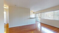 Located at 2059 W Artesia Blvd in Torrance, California, this single-floor unit offers a well-organized layout with a variety of functional living spaces. The open living area is a standout feature, showcasing warm hardwood flooring that gleams with natural light streaming in through large windows and a sliding glass door that leads to a private balcony with outdoor views. A ceiling fan adds comfort to the space, while vertical wood panel accents on one wall lend a subtle design character. A half-wall divider with a bar-height ledge separates the living area, adding architectural interest without closing off the open feel.

The galley-style kitchen is efficiently laid out with white cabinetry, dark countertops, stainless steel appliances including a gas range and microwave, and a sink with ample workspace on both sides. Hardwood flooring continues throughout the kitchen, maintaining a cohesive aesthetic.

The bedroom offers plush carpeting and a wide window dressed with vertical blinds, allowing for adjustable natural light and privacy. The full bathroom is clean and bright, featuring a tiled tub-and-shower combination, a window for natural ventilation, a toilet, and a vanity with a light countertop. Hardwood-style flooring completes the bathroom's fresh, neutral look throughout this well-maintained Torrance residence.