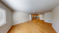 Located at 1402 E 69th St in Tacoma, WA, this single-floor, 2-bedroom, 2-bathroom residence offers a functional and comfortable layout throughout. Warm honey-toned hardwood floors flow consistently through every room, creating a cohesive and inviting atmosphere.

The kitchen is well-equipped with stainless steel appliances — including a refrigerator, electric range, microwave, and dishwasher — complemented by light maple cabinetry, dark countertops, and recessed lighting. Conveniently adjacent to the kitchen is a dedicated in-unit laundry alcove housing a full-size washer and dryer.

The open living room receives natural light through a large window fitted with blinds, lending the space a bright and airy feel. Both bedrooms are comfortably sized, each featuring windows with natural light, closets, and clean neutral walls. The primary bedroom includes an en-suite walk-through layout connecting to a closet and bathroom access. The bathrooms feature maple vanity cabinetry with dark countertops, large mirrors, and a tub-shower combination. A connecting hallway ties the rooms together efficiently. The overall design is clean, neutral, and move-in ready.
