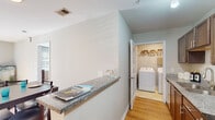 Located at 206 Cedar Branch Ln in Wilmington, NC, this single-floor residence offers a thoughtfully designed layout with a clean, modern aesthetic throughout. The open-concept kitchen and dining area serves as the heart of the home, featuring dark espresso cabinetry, granite countertops, stainless steel appliances including a refrigerator, range, and microwave, and a breakfast bar peninsula that connects seamlessly to the dining space. Warm hardwood-style flooring flows throughout the main living areas, complementing the neutral gray-toned walls and creating a bright, welcoming atmosphere. The living room is generously sized, with natural light filtering in through slatted blinds. Bedrooms are carpeted for added comfort, with one room well-suited as a home office or guest space, complete with a ceiling fan and window. The walk-in closet offers ample storage with wire shelving systems. Two full bathrooms include tub/shower combinations with brushed nickel fixtures and tile flooring. A dedicated in-unit laundry room houses a full-sized washer and dryer with overhead shelving for additional storage. The overall design balances functionality and comfort, making this Wilmington residence a practical and inviting place to call home.