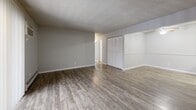 This 2-bedroom, 2-bathroom unit at Vantage Point in Denver, Colorado offers a practical and comfortable single-floor layout. The open living room features wood-style plank flooring, a textured ceiling, baseboard heating, and a wall-mounted A/C unit. A ceiling fan adds comfort, while a sliding glass door with vertical blinds fills the space with natural light and provides access to an outdoor patio area. The galley-style kitchen is efficiently designed with white cabinetry, gray laminate countertops, a stainless steel sink, and white appliances including a coil-top range and refrigerator, all set on light wood-style flooring. Both bedrooms are carpeted and offer a quiet, neutral palette. The primary bedroom is generously sized and includes a window with natural views of surrounding trees. The second bedroom features a full-width closet with louvered bifold doors. Three closets throughout the unit provide ample storage. The two bathrooms include a vanity with under-cabinet storage, well-lit mirrors, and a tub/shower combination with clean white tile surround and brushed nickel fixtures. Neutral gray tones and consistent finishes throughout lend the unit a cohesive, move-in-ready feel.