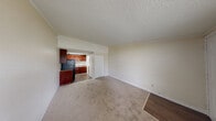 This compact studio unit at 15750 NW 7th Ave in Miami, FL offers an efficient and functional single-floor layout. The open living area features neutral-toned carpet flooring, cream-colored walls, and a textured ceiling, creating a clean and simple aesthetic throughout. A large window fitted with blinds allows natural light to fill the space while providing views of the surrounding greenery outside. A wall-mounted HVAC unit ensures climate control, and a dedicated entryway with a closet offers convenient storage.

The kitchenette is seamlessly integrated into the living space, featuring rich, dark wood cabinetry, black appliances including a refrigerator and stove, and a countertop with a sink. The hardwood-style flooring in the kitchen area provides a practical contrast to the carpeted living zone.

The bathroom is straightforward and functional, equipped with a vanity featuring a white countertop and sink, a mirror, and tiled flooring. The textured walls and clean fixtures maintain the unit's consistent, utilitarian design.

An additional closet adjacent to the living area provides extra storage solutions. Overall, this studio presents a no-frills, practical living space well-suited for those seeking an efficient layout in Miami's North Dade area.