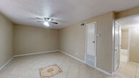 This single-story space presents a practical and cohesive layout highlighted by light beige ceramic tile flooring throughout. The main living area is spacious and open, featuring a ceiling fan with integrated lighting, a textured popcorn ceiling, and neutral-toned walls that create a calm, understated atmosphere. A decorative tile medallion inset into the floor serves as a subtle focal point. Natural light enters through blinded windows, and HVAC vents along with a wall-mounted thermostat indicate climate control throughout.

The bedrooms mirror the living area's design, each equipped with ceiling fans, tile flooring, and windows fitted with horizontal blinds that allow adjustable natural light. The rooms offer clean, uncluttered spaces suitable for a variety of furniture arrangements.

The kitchen is efficiently designed in a galley-style configuration, featuring dark cabinetry, granite-style countertops, a stainless steel sink, a black electric range, and a stone-tile backsplash that adds texture and visual interest to the space.

The bathroom includes a full tub and shower combination with tile surround, a window for ventilation, white upper cabinetry, and a vanity with a granite-style countertop and dark lower cabinet, maintaining a consistent design language with the rest of the space.