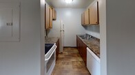 Located at 3600 E Sixth St in Sioux Falls, South Dakota, this single-floor unit offers a practical and straightforward layout suited for everyday living. The main living area features wood-look plank flooring and a textured ceiling, with a pass-through counter connecting it to the adjacent spaces, creating an open and functional feel. A front entry door opens directly into the living area, which is bathed in neutral tones throughout.

The galley-style kitchen is efficiently designed with warm wood cabinetry on both sides, dark granite-style countertops, a double basin sink, and white appliances including a range, refrigerator, and dishwasher. The kitchen flooring continues the wood-look theme found throughout the main areas.

The carpeted bedrooms provide a softer underfoot experience, each featuring textured ceilings and windows with blinds that allow natural light to filter in. One bedroom is equipped with a ceiling fan and light fixture, while another includes a wall-mounted air conditioning unit for individual climate control.

The bathroom is clean and functional, featuring a vanity with warm wood cabinetry, a toilet, and a full tub-shower combination with white surround. Dark-trimmed doors are consistent throughout, adding a subtle contrast to the light-colored walls across the unit.