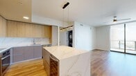 Located along Tampa's iconic Riverwalk Trail, this modern 2-bedroom, 3-bathroom residence offers a thoughtfully designed open-concept layout with high-end finishes throughout. The chef's kitchen is a standout centerpiece, showcasing a large waterfall-edge quartz island, warm wood cabinetry, a marble-style tile backsplash, stainless steel appliances, and sleek pendant lighting — all flowing seamlessly into the living area with warm hardwood-style flooring. The spacious living room features floor-to-ceiling sliding glass doors that frame sweeping views of the Tampa waterfront and cityscape, flooding the space with natural light. Both bedrooms are generously sized, carpeted for comfort, and fitted with ceiling fans and dramatic floor-to-ceiling windows offering breathtaking river and city views. The primary bedroom includes a walk-in closet with built-in wire shelving. Three well-appointed bathrooms serve the residence, including one featuring a frameless glass walk-in shower with elegant marble-style tile. An in-unit stacked washer and dryer adds everyday convenience. With three closets providing ample storage and a clean, contemporary aesthetic throughout, this residence delivers a refined urban living experience in one of Tampa's most sought-after waterfront locations.