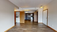 Located at 8808 North Indian Trail Road in Spokane, Washington, unit 4301 is a thoughtfully designed single-floor residence that balances modern finishes with functional living. Rich wood-tone luxury vinyl plank flooring flows through the main living areas, complemented by warm wood baseboards and neutral gray walls that create a clean, contemporary aesthetic throughout.

The open living area features a glass-panel door that floods the space with natural light and provides views of the surrounding neighborhood. The kitchen is outfitted with dark espresso cabinetry, granite-style countertops, stainless steel appliances including a refrigerator, microwave, and range, and a classic subway tile backsplash with decorative accent tiles. A dedicated laundry area with a full-size washer and dryer is conveniently tucked behind cabinetry near the main living space.

Bedrooms are carpeted for comfort and feature large windows that invite natural light and outdoor views. A spacious walk-in closet with multi-tier wire shelving provides generous storage. The bathroom is finished with a dark navy vanity, granite-style countertop, subway tile backsplash, and a large mirror. A wide hallway connects the rooms, enhancing the overall sense of flow and space within the unit.
