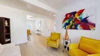 Located in Miami's vibrant Upper East Side neighborhood, this 2-bedroom, 2-bathroom single-story residence combines modern design with functional living. Light wood-look flooring runs throughout, complementing crisp white walls and creating a clean, airy aesthetic across every room.

The open-concept living area is bright and welcoming, with large windows that invite natural light and offer views of the lush surroundings. The kitchen features white shaker cabinetry, a light stone countertop with a breakfast bar, and stainless steel appliances including a gas range and refrigerator — ideal for both casual dining and entertaining.

The primary bedroom offers a comfortable, well-proportioned retreat with warm lighting and tasteful wall art, while the second bedroom benefits from dual windows framing tropical greenery, filling the space with natural light. Both rooms feature the same light flooring that flows throughout the home.

The two bathrooms are finished with elegant marble-style tile. The first bathroom showcases floor-to-ceiling marble tilework with a wall-mounted sink and sleek chrome fixtures. The second features matching marble tile, a pedestal sink, and a matte black faucet. A connecting hallway links all rooms efficiently, completing this thoughtfully designed Miami residence.