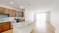 Located in Leawood, Kansas, this single-floor, 2-bedroom, 2-bathroom residence offers a thoughtfully designed open-concept layout. The kitchen is a standout feature, boasting rich warm-toned cabinetry, stainless steel appliances, a glass tile backsplash, and a generous granite-topped island with elegant pendant lighting overhead. Light wood-style flooring flows seamlessly from the kitchen into the bright, airy living room, which is bathed in natural light from large sliding glass doors that open to an outdoor area. Both bedrooms are carpeted for comfort and include ceiling fans and windows with blinds. The primary bedroom is a comfortable size and connects to a well-appointed full bathroom featuring a double-sink vanity with granite countertops, warm wood cabinetry, large-format tile flooring, and a combined soaking tub and tiled shower. Two closets provide ample storage, including a walk-in closet with wire shelving. A hallway connects the rooms efficiently, maintaining a clean and functional flow throughout the home. Recessed lighting and a crisp, neutral color palette give the entire space a modern, polished ambiance.