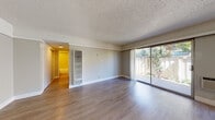 Located at 1365 Mt Pisgah Rd in Walnut Creek, California, this single-floor residence offers a comfortable and functional layout with a clean, neutral aesthetic throughout. The expansive living area is a standout feature, showcasing light-toned hardwood-style flooring, textured ceilings, and crisp white crown molding. Large sliding glass doors flood the space with natural light and provide direct access to a private outdoor patio area, where mature flowering plants and greenery create a pleasant garden backdrop. A wall-mounted HVAC unit ensures year-round climate comfort.

The kitchen is well-appointed with rich dark wood cabinetry, light quartz countertops, and a full suite of stainless steel appliances including a refrigerator, dishwasher, and range. A range hood and ample upper and lower cabinet storage make this an efficient and attractive cooking space.

The bedroom features plush carpeting, neutral-toned walls, and a generously sized window that frames views of the surrounding trees, lending a calm and serene atmosphere. The bathroom is finished with warm wood vanity cabinetry, quartz countertops, a full tub and shower combination with clean tile surround, and a large mirror. The overall ambiance of the home is bright, practical, and move-in ready.