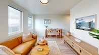 Located in the heart of Tacoma, WA, this thoughtfully designed 2-bedroom, 2-bathroom residence offers a modern, efficient layout that makes excellent use of its space. Light wood-style flooring flows throughout, complementing the bright, neutral palette that defines the unit's clean aesthetic.

The kitchen is outfitted with dark cabinetry, black countertops, and stainless steel appliances including an electric range, microwave, and dishwasher. Light upper cabinets and under-cabinet lighting provide a striking contrast, while a deep single-basin sink with a matte black faucet adds a contemporary touch. The kitchen opens seamlessly into the combined living and dining area, where large windows frame views of the Tacoma cityscape, filling the space with natural light. The living area offers a comfortable, open feel with room for both a seating arrangement and a dining table.

Both bedrooms are well-proportioned, each featuring windows with outdoor views and light-toned walls that create a calm, restful atmosphere. The primary bedroom provides a comfortable retreat with ample natural light. The two bathrooms are clean and functional, each featuring a shower-tub combo with matte black fixtures and modern vanities with rectangular sinks. A hallway connects the private areas of the unit, contributing to a practical and well-organized floor plan.