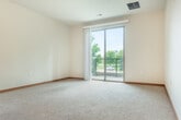 Located at 5120 Brookside Dr in Madison, WI, this well-appointed one-bedroom, one-bathroom unit offers a thoughtfully designed layout across a single floor. The open-concept kitchen and living area serves as the heart of the home, featuring rich hardwood flooring, warm wood cabinetry, stainless steel appliances, and a granite-topped island with pendant lighting overhead. Track lighting illuminates the kitchen workspace, while a seamless transition to the carpeted living area creates a comfortable and functional shared space. A sliding glass door in the living room opens to a private patio with cable-rail balcony fencing, offering serene views of lush, landscaped greenery. The bedroom is generously sized, bathed in natural light through large windows that overlook mature trees, and finished with plush carpeting. A spacious walk-in closet with built-in shelving and hanging rods provides ample storage. The full bathroom includes a wood-toned vanity, tile flooring, and a full tub-shower combination. Additional conveniences include a dedicated laundry area and a second closet for extra storage. The overall ambiance is clean, warm, and inviting, making this unit a comfortable residence in a tranquil Madison setting.