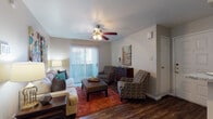 This single-floor residence offers a thoughtfully organized layout with a variety of comfortable living spaces. The living room serves as the heart of the home, featuring rich hardwood-style flooring, a ceiling fan with integrated lighting, and a large sliding glass door fitted with vertical blinds that allows abundant natural light to fill the room. The space comfortably accommodates a full seating arrangement, making it ideal for both relaxing and entertaining.

Adjacent to the living area is a dedicated dining space, finished with the same hardwood-style flooring and accented by warm-toned walls. The galley-style kitchen is equipped with dark cabinetry, granite-look countertops, and black appliances including a refrigerator and electric range, offering a practical and efficient cooking environment.

The residence includes two carpeted bedrooms, each providing a calm and comfortable retreat. One bedroom benefits from a window with natural light and direct access to a walk-in closet and an adjoining bathroom. The bathroom features a granite-look vanity countertop with dark cabinetry and a well-lit mirror, contributing to a clean and functional design. Throughout the home, a consistent neutral color palette and coordinated décor create a cohesive and inviting atmosphere.
