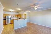 Located at 301 Lakeshore Blvd N in Slidell, Louisiana, this single-story, one-bedroom, one-bathroom unit offers a thoughtfully designed layout across a comfortable footprint. Light-toned hardwood floors run throughout the main living areas, complemented by crown molding and neutral wall tones that create a clean, welcoming ambiance.

The open-concept living, dining, and kitchen area forms the heart of the unit. The kitchen is well-equipped with honey-toned wood cabinetry, laminate countertops, stainless steel refrigerator, a black range with overhead ventilation, a dishwasher, and a peninsula breakfast bar with seating overhang — ideal for casual dining. A separate pantry provides additional storage.

The living area is bright and airy, highlighted by a ceiling fan and French doors that open to a private patio, allowing natural light to pour in. The bedroom is carpeted for comfort, features its own ceiling fan, and is served by multiple closets, including a spacious walk-in closet with wire shelving. The bathroom includes wood cabinetry for storage. Additional conveniences include a dedicated laundry area and an entrance hallway. The unit offers abundant closet space throughout, making it a highly functional and comfortable residence.