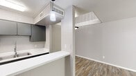 This two-story, 1-bedroom, 1-bathroom home in Dallas, TX offers a well-designed layout spread across two floors. The main level features a bright living room with wood-look flooring, a classic wood-burning fireplace framed by a white surround, and multiple windows that invite generous natural light. The kitchen is efficiently arranged with dark grey cabinetry, white countertops, a double-basin sink, black appliances, and a pendant light overhead. A breakfast bar peninsula connects the kitchen to the living area, creating an open and functional flow. A staircase with a white balustrade leads to the upper level, where the spacious primary bedroom awaits. This room features plush wall-to-wall carpeting, a ceiling fan with light fixture, and a window with outdoor views. An adjoining walk-in closet provides ample storage. The full bathroom is appointed with grey cabinetry, a white countertop vanity, a bold black-framed mirror, stylish globe lighting, a window for natural light, and a tub/shower combination. Wood-look flooring in the bathroom complements the overall neutral and cohesive aesthetic throughout the home, giving it a clean, modern feel.