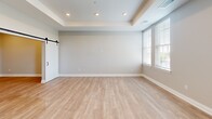 Located at 298 W Monroe St in Dundee, Michigan, this well-appointed unit offers a modern, open-concept layout with a clean, neutral aesthetic throughout. Light hardwood-style flooring runs continuously across the entire space, lending a cohesive and airy feel.

The combined kitchen and living area serves as the heart of the unit. The kitchen is outfitted with floor-to-ceiling dark wood cabinetry, white quartz countertops, a stainless steel undermount sink with a matte black faucet, and a full suite of stainless steel appliances including a refrigerator with ice maker, range, microwave, and dishwasher. Recessed lighting illuminates the space effectively. The adjacent living area features a tray ceiling, recessed lighting, and a stylish sliding barn door with a black hardware track — a standout design element that adds modern farmhouse character.

Large windows invite generous natural light into the living area, offering pleasant outdoor views. The bathroom is finished with a wood-toned vanity, white countertop, matte black fixtures, and a large mirror. The walk-in closet provides practical wire shelving and hanging rods for organized storage. A hallway connects the rooms efficiently. Overall, the unit presents a contemporary, move-in-ready interior with quality finishes throughout.