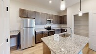 Located at 4616 Blue Diamond Way in Knoxville, Tennessee, this single-floor home offers a clean, modern design throughout. The kitchen is a standout feature, showcasing rich dark cabinetry, granite countertops, stainless steel appliances, a central island with a sink, and stylish pendant lighting — all set above light hardwood-style flooring that flows seamlessly through the main living areas. The open layout connects the kitchen to adjacent living spaces, with a dedicated laundry area conveniently accessible nearby. The primary bedroom is carpeted for comfort and includes a walk-in closet with wire shelving organization systems, along with a stylish barn door leading to the en-suite bathroom. That bathroom features a granite-topped dark wood vanity, a tub-shower combination, and matching hardwood-style flooring. Additional bedrooms are bright and well-sized, benefiting from natural light through windows and ceiling fans for year-round comfort. A second full bathroom mirrors the same quality finishes with a granite vanity and tub-shower combo. Throughout the home, neutral warm tones, white panel doors, and clean lines create a cohesive and inviting ambiance well-suited for comfortable everyday living.