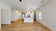 Located at 701 Saginaw Blvd in Saginaw, TX, this well-appointed 3-bedroom, 2-bathroom home offers a thoughtfully designed single-floor layout with a clean, contemporary aesthetic throughout. Light wood-look flooring flows seamlessly across the living, dining, and kitchen areas, creating a warm and cohesive feel. The open-concept kitchen is a standout feature, boasting a large white quartz island with an undermount sink and matte black faucet, two-tone cabinetry in white and slate gray, stainless steel appliances, and dramatic black pendant lighting. The living and dining areas benefit from generous natural light, complemented by ceiling fans for comfort. The primary bedroom is a spacious retreat with access to a luxurious en-suite bathroom featuring an extended dual-sink vanity with quartz countertops, gray cabinetry, matte black fixtures, a soaking tub, a separate shower, and a walk-in closet with built-in shelving. The additional bedrooms are bright and well-sized, each with windows that invite natural light. The second bathroom mirrors the modern design with a gray vanity and framed mirror. A private balcony rounds out this home's appealing features.