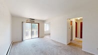 Located at 1631 Carl St in Lauderdale, Minnesota, this single-floor unit offers three bedrooms, one bathroom, a kitchen, and a hallway within a well-organized layout. The living area features neutral-toned carpet, baseboard heating, and a wall-mounted air conditioning unit, with sliding glass doors that bring in natural light and provide outdoor access. A second window in the living space further brightens the room. The kitchen is outfitted with warm wood-toned cabinetry lining both walls, a white electric range, a refrigerator, and a single-basin sink, all set over wood-look flooring that adds a clean, practical touch. The generously sized primary bedroom includes a ceiling fan with light, a double sliding-door closet, and warm carpeting. The two additional bedrooms also feature ceiling fans, carpeted floors, baseboard heating, and windows that allow natural light to filter in. The full bathroom is finished with white subway tile walls, mosaic tile flooring, a pedestal sink, a mirrored medicine cabinet with overhead lighting, and a bathtub. A hallway connects the bedrooms and bathroom, completing this straightforward and functional floor plan.
