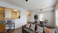This single-floor residence is thoughtfully designed to maximize functionality and comfort across its interconnected living spaces. The open-concept living room serves as the heart of the home, featuring wood-style plank flooring, a ceiling fan, and an abundance of natural light provided by multiple large windows dressed with white blinds. A sliding glass door connects the living area to an exterior space, enhancing the sense of openness. Adjacent to the living room, a dedicated dining area provides a practical space for meals.

The kitchen is accessible via a pass-through counter with bar seating for two, making it ideal for casual dining and socializing. It is equipped with white cabinetry, warm-toned countertops, a stainless drop-in sink, an electric range, and an over-the-range microwave.

The bedroom is a calm, neutral retreat finished with the same wood-style flooring. It accommodates a full-sized bed comfortably and features a ceiling fan, a window for natural light, and wall space suitable for décor or artwork.

The bathroom is clean and efficiently laid out, featuring a single-sink vanity with white cabinetry, warm countertops, tile flooring, and a tub-shower combination with sliding glass doors.