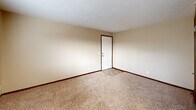 Located at 711 E Sharpe Ave in Spokane, Washington, this two-bedroom, one-bathroom unit offers a practical and efficient single-floor layout. The interior features warm, neutral-toned walls throughout, complemented by wall-to-wall carpeting in the living and bedroom areas and tile flooring at the entryway and kitchen transition zones.

The open living area is anchored by a large picture window fitted with horizontal blinds, allowing natural light to fill the space while offering views of the surrounding neighborhood. A baseboard heating system runs along the exterior walls, providing consistent warmth throughout the unit.

The kitchen is compactly arranged with wood-toned cabinetry and includes a white electric range, making efficient use of the available space.

The generously sized primary bedroom features a wall-mounted air conditioning unit, a window with blinds for natural light and privacy, and a sliding-door closet. The second bedroom is well-proportioned, also carpeted, and includes its own window and baseboard heating.

The bathroom is equipped with a full tub and shower combo, surrounded by light-toned tile work and fitted with chrome fixtures, offering a clean and functional finish.

Throughout the unit, textured ceilings and dark wood trim framing doors and windows add a consistent, cohesive design detail. This unit provides a straightforward, comfortable living space in a convenient Spokane location.