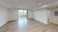 This thoughtfully designed single-floor residence offers a clean, modern aesthetic throughout, with light wood-style flooring and crisp white walls creating a bright and cohesive living environment. Recessed lighting is featured across all rooms, contributing to a well-lit and contemporary atmosphere.

The open-concept living area is a standout feature, offering generous space and direct access to a private balcony through large sliding glass doors. The balcony provides views of the surrounding neighborhood, including tree-lined streets and neighboring architecture, allowing natural light to pour into the space.

The kitchen is efficiently laid out in an L-shape configuration, outfitted with white flat-front cabinetry, neutral-toned countertops, a glass tile backsplash, and a full suite of stainless steel appliances including a gas range, built-in microwave, dishwasher, and refrigerator.

The bedrooms are well-proportioned, each featuring light wood flooring, recessed lighting, and window coverings for privacy. Additional rooms provide flexible space suitable for a home office or guest room.

The full bathroom features a sliding-door tub and shower combo with clean tile surround, a toilet, and light wood flooring. A dedicated laundry area includes a stacked washer and dryer unit alongside ample cabinetry and counter space for added convenience.