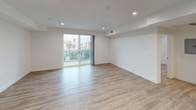 This thoughtfully designed single-floor residence offers a clean, modern aesthetic throughout, with light wood-style flooring and crisp white walls creating a bright and cohesive living environment. Recessed lighting is featured across all rooms, contributing to a well-lit and contemporary atmosphere.

The open-concept living area is a standout feature, offering generous space and direct access to a private balcony through large sliding glass doors. The balcony provides views of the surrounding neighborhood, including tree-lined streets and neighboring architecture, allowing natural light to pour into the space.

The kitchen is efficiently laid out in an L-shape configuration, outfitted with white flat-front cabinetry, neutral-toned countertops, a glass tile backsplash, and a full suite of stainless steel appliances including a gas range, built-in microwave, dishwasher, and refrigerator.

The bedrooms are well-proportioned, each featuring light wood flooring, recessed lighting, and window coverings for privacy. Additional rooms provide flexible space suitable for a home office or guest room.

The full bathroom features a sliding-door tub and shower combo with clean tile surround, a toilet, and light wood flooring. A dedicated laundry area includes a stacked washer and dryer unit alongside ample cabinetry and counter space for added convenience.