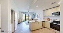 Located at 7301 Lake Bank Loop in Fort Myers, FL, this well-appointed one-bedroom, one-bathroom residence offers a thoughtfully designed single-level floor plan. Light wood-style flooring flows throughout, complementing the bright, neutral color palette that gives the space an airy, coastal feel.

The open-concept kitchen and living area form the heart of the home. The kitchen is outfitted with stainless steel appliances, cream cabinetry extending to the ceiling, a clean white quartz peninsula with seating, a deep undermount sink, and a tile backsplash. The living area is generously sized, anchored by a ceiling fan and sliding glass doors that open to a private patio overlooking scenic water and green grounds — an ideal setting to enjoy Florida's outdoor lifestyle.

The hallways are lined with clean white panel doors and lead to the well-proportioned bedroom, which features a large window with lush tropical views, warm ambient lighting, and a dedicated closet. A separate pantry and utility room add practical storage and functionality.

The bathroom showcases marble-style tile in the walk-in shower with a gold-framed glass enclosure, botanical-inspired wallcovering accents, and refined fixtures. A dedicated laundry area completes this efficiently designed, move-in-ready residence.