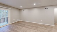 This two-floor unit at Countryside Apartments in Hackettstown, NJ offers a well-designed layout spread across two levels, with the main living areas occupying the upper floor. Light wood-tone luxury vinyl flooring runs throughout the primary living spaces, lending a clean, contemporary aesthetic complemented by neutral gray-toned walls and crisp white trim.

The living room is a generously proportioned space highlighted by recessed lighting and a sliding glass door that opens to a private balcony overlooking a wooded backdrop, bringing in natural light and outdoor views. Adjacent to the living room, the kitchen is efficiently arranged with white shaker cabinetry, granite-style countertops, stainless steel appliances including a gas range, built-in microwave, dishwasher, and refrigerator, plus a built-in desk nook beneath a window.

The spacious primary bedroom features plush wall-to-wall carpeting, a ceiling fan with light fixture, a window with natural light, and direct access to the full bathroom. The bathroom is finished with large-format neutral tile surrounding a soaking tub and overhead rain showerhead. An additional flexible room with a closet and recessed lighting offers versatile use. A staircase connects the entry-level foyer to the main floor above.