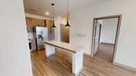 Located at 80 W Oxmoor Rd in Birmingham, AL, this well-appointed one-bedroom, one-bathroom unit offers a thoughtfully designed single-floor layout that maximizes comfort and functionality. The open-concept living and kitchen area serves as the heart of the home, featuring warm wood-look luxury vinyl plank flooring that runs seamlessly throughout the space. The kitchen is a standout, equipped with a full suite of stainless steel appliances — including a French door refrigerator, electric range, built-in microwave, and dishwasher — complemented by rich wood-toned cabinetry, a classic white subway tile backsplash, and granite countertops. A central kitchen island with a granite surface and stylish pendant lighting above provides additional prep space and a casual dining option. The living area benefits from large windows that invite natural light and offer views of the surrounding greenery. The generously sized bedroom includes a ceiling fan, multiple windows, and access to a dedicated closet. The bathroom is finished with granite countertops, wood-toned cabinetry, and a tiled walk-in shower. Additional conveniences include a pantry, in-unit laundry, and a clean, neutral color palette that lends a bright, modern ambiance throughout.