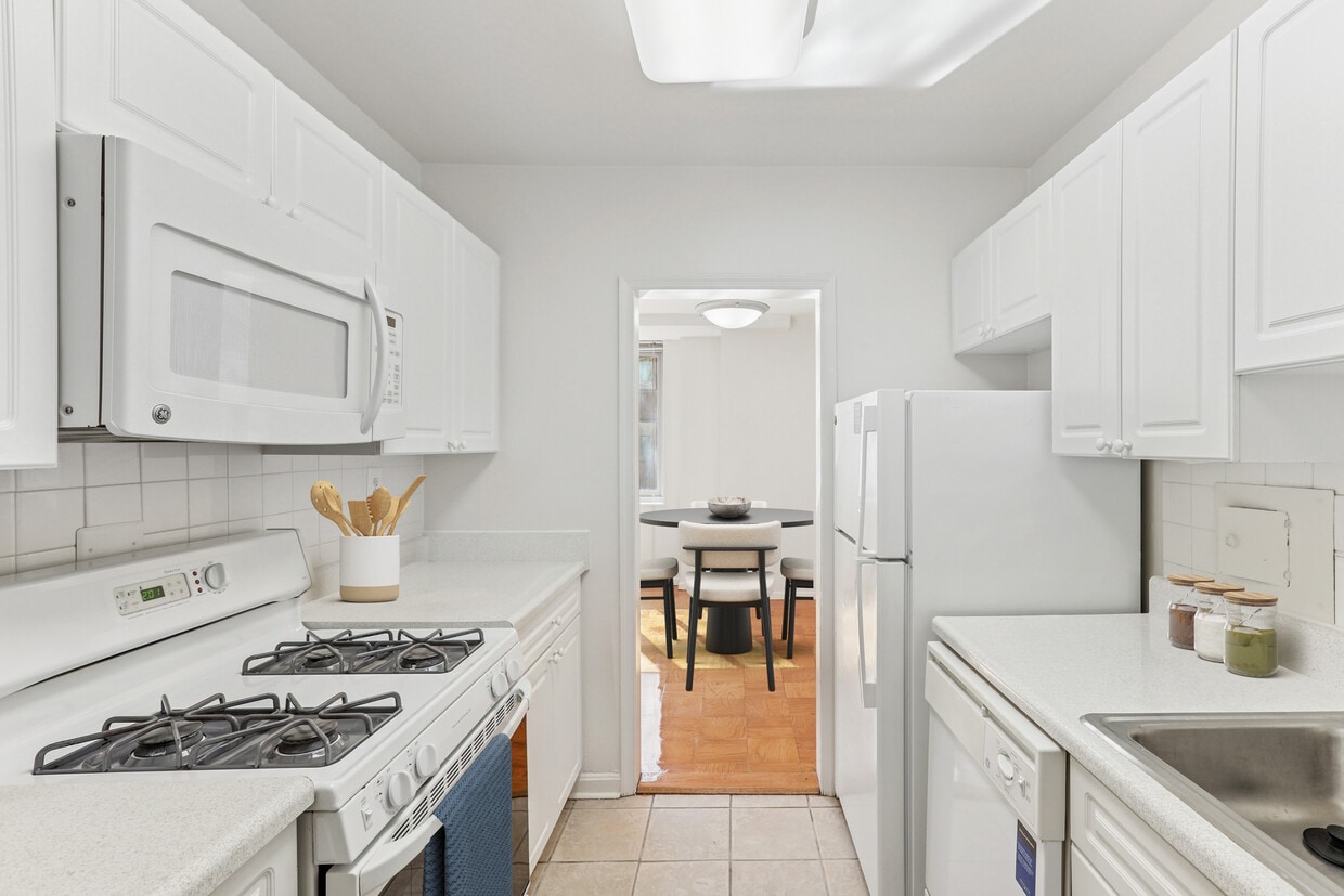 Kitchen with white cabinetry, white laminate countertops, white tile backsplash, white appliances, and hard surface flooring - The Statesman