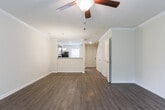 This two-story residence in Savannah, Georgia offers a well-organized layout across both levels, combining practical finishes with comfortable living spaces. The main floor features an open living area with warm wood-look laminate flooring, crown molding, and a ceiling fan, creating a welcoming atmosphere. A sliding glass door allows natural light to fill the space and provides outdoor access. The living area connects seamlessly to the kitchen, which is equipped with rich medium-toned wood cabinetry, light granite-style countertops, a double sink, and a full suite of stainless steel appliances including a range, microwave, dishwasher, and refrigerator. A carpeted staircase with a white-painted banister and metal handrail leads to the upper level. The second floor hosts carpeted bedrooms, each outfitted with ceiling fans and natural light from windows with blinds. Bedrooms include closet space, with at least one featuring a reach-in closet. The bathrooms feature clean, white tub and shower combinations with panel surrounds and chrome fixtures. Throughout the home, neutral wall tones and consistent finishes provide a cohesive and functional living environment.