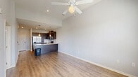Located at 8201 Quivira Rd in Lenexa, Kansas, this thoughtfully designed one-bedroom, one-bathroom residence offers a comfortable and modern living experience on a single floor. The open-concept layout seamlessly connects the kitchen and living room, creating an inviting, functional space. The kitchen is a standout feature, showcasing rich dark-espresso cabinetry, granite countertops, a subway tile backsplash, stainless steel appliances including a refrigerator, range, microwave, and dishwasher, and elegant pendant lighting above the peninsula island. Light hardwood-style flooring flows throughout the main living areas, adding warmth and continuity. The living room is bathed in natural light through large windows with blinds and features soaring ceilings, a ceiling fan, and a glass door leading to a private balcony with outdoor views. The spacious primary bedroom is finished with plush carpet, a ceiling fan, a generously sized closet, and a large window overlooking the surrounding greenery. The full bathroom includes a walk-in shower with built-in shelving and clean white tile surround. The overall ambiance is bright, clean, and contemporary, making this a well-rounded and move-in-ready residence.