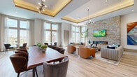 Located at 2906 Delafield St in Houston, TX, this thoughtfully designed single-floor space offers an open-concept layout that seamlessly connects the living room, dining room, and kitchen. Soaring ceilings and floor-to-ceiling windows flood the interior with abundant natural light, framing views of the surrounding neighborhood and creating an airy, welcoming atmosphere throughout.

The living area serves as the centerpiece of the space, anchored by a dramatic full-height stacked stone accent wall featuring a sleek linear fireplace. Light wood-look tile flooring runs throughout, complementing the warm, neutral color palette. Coffered ceiling details with integrated lighting and contemporary chandeliers add architectural refinement to the open layout.

The kitchen is outfitted with dark cabinetry, granite countertops, subway tile backsplash, stainless steel appliances, and a large waterfall-edge island with seating for multiple guests. Glass-panel sliding doors connect the kitchen to adjacent areas, enhancing the sense of openness and flow.

The dining area features a substantial wood table and upholstered seating, while a cozy breakfast nook with floor-to-ceiling windows and a round marble-top table offers a bright, intimate setting. Together, these spaces deliver a cohesive, modern aesthetic that balances elegance with everyday functionality.