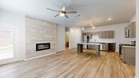 This well-designed 2-bedroom, 2-bathroom single-floor home offers a thoughtful open-concept layout that seamlessly connects the living, dining, and kitchen areas. The living room is anchored by a sleek linear fireplace set against a full-height tiled accent wall, creating a striking focal point. Light wood-look flooring runs throughout the main living areas, complemented by a ceiling fan overhead. Natural light enters through a glass front door, enhancing the bright, airy atmosphere.

The kitchen is a standout feature, equipped with stainless steel appliances including a refrigerator and dishwasher, warm-toned shaker-style cabinetry, granite countertops, a classic subway tile backsplash, and a central island with open shelving — ideal for both cooking and entertaining. Stylish pendant lights hang above the island, adding a modern touch.

Both bedrooms are comfortably sized and carpeted, with the primary bedroom featuring a ceiling fan and a window with natural light. Each bedroom includes a dedicated closet. The two bathrooms mirror each other in design, featuring granite-topped vanities with shaker cabinetry, tub-shower combinations, and wood-look tile flooring. A dedicated laundry area with washer/dryer hookups adds everyday convenience to this well-appointed home.