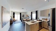 This single-story residence is designed with a clean, contemporary aesthetic that flows cohesively throughout. The open-concept living, dining, and kitchen area forms the heart of the space, where wood-look plank flooring, crisp white walls, and black-accented window treatments establish a modern monochromatic tone. The kitchen is well-appointed with light wood cabinetry, white quartz countertops, a stainless steel sink integrated into the island, and a full suite of stainless steel appliances including a range, microwave, and refrigerator. Track lighting overhead adds a refined finishing detail.

The living area is bright and welcoming, benefiting from a sliding glass door that invites natural light and provides outdoor access. The dining space connects seamlessly between the kitchen and living room, supporting a natural flow for everyday living.

Each bedroom features wood-look flooring, ceiling fans, and windows with layered blinds and drape treatments for adjustable light control. Walk-in closet storage is available, and the bedrooms carry the same calm, neutral palette found throughout the unit.

The bathrooms are finished with clean white walls, recessed lighting, wood-toned vanities with ample drawer storage, and glass-enclosed showers, presenting a polished and functional design.