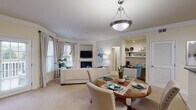 Located at 2000 Crossroads Manor Ct in Cary, NC, this single-floor residence offers a thoughtfully designed layout with a warm, inviting ambiance throughout. The open-concept living and dining area serves as the heart of the home, featuring a built-in fireplace with tile surround, a wall-mounted TV niche, and crown molding that adds a refined architectural touch. A bay of large windows with plantation shutters and drapes floods the space with natural light, while a door provides direct outdoor access. A pendant light anchors the dining area, which flows seamlessly into the living room. The kitchen features warm wood cabinetry, dark countertops, tile backsplash, stainless steel appliances, and tile flooring, with convenient access to additional storage and utility areas. A dedicated study nook with built-in shelving offers a practical workspace. The primary bedroom is generously sized with multiple windows, plush carpet, and a ceiling fan, while the second bedroom also enjoys natural light and comfortable proportions. The primary bathroom includes a walk-in tiled shower with glass doors, and a second full bathroom features a tiled tub-shower combination. Throughout, the residence maintains a cohesive, light-toned palette that enhances the sense of openness and ease of living.