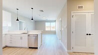 This thoughtfully designed 2-bedroom, 2-bathroom single-floor residence offers a clean, modern aesthetic with a bright and open feel throughout. The open-concept kitchen and living area serves as the heart of the home, featuring a large center island with white quartz countertops, white shaker-style cabinetry, a stainless steel refrigerator and dishwasher, and sleek pendant lighting. Light-toned hardwood flooring flows seamlessly across the entire living space, enhancing the airy atmosphere.

The living area is bathed in natural light from wide sliding windows that frame outdoor views, creating an inviting and comfortable space. Both bedrooms continue the light hardwood flooring and neutral wall tones, with large windows that bring in ample daylight and exterior views. The generously sized primary bedroom includes a walk-in closet equipped with wire shelving for organized storage.

The two bathrooms are finished with striking marble-look tile walls and flooring. One bathroom features a combination soaking tub and shower with a handheld fixture, while the second offers a walk-in shower — both appointed with polished chrome hardware. A dedicated closet with a louvered door provides additional storage. The overall design is clean, contemporary, and move-in ready.