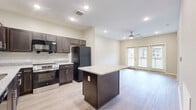 Located at 1590 Agape Way in Decatur, GA, this well-designed one-bedroom, one-bathroom home offers a thoughtful single-floor layout that maximizes functionality and comfort. Light-toned wood-style flooring flows consistently throughout, creating a cohesive and clean aesthetic.

The open-concept kitchen and living area serves as the heart of the home. The kitchen is outfitted with rich dark-wood cabinetry, granite countertops, a full suite of black appliances including a refrigerator, dishwasher, microwave, and stainless steel range, as well as a central island with additional granite surface space—ideal for meal prep or casual dining. Recessed lighting illuminates the kitchen, while the adjacent living room benefits from natural light streaming through French doors that open to a private balcony. A ceiling fan adds to the comfort of the living space.

The spacious bedroom features neutral walls and connects to two closets, one of which is a walk-in equipped with wire shelving systems for organized storage. A dedicated laundry area with a full-size washer and dryer is conveniently located nearby.

The bathroom is finished with tile flooring, a granite-topped dark wood vanity, a wall mirror, and a full-size soaking tub with shower.