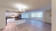 Located at 4400 E West Hwy in Bethesda, Maryland, this single-floor residence offers a well-designed open-concept layout with a clean, contemporary aesthetic. Light hardwood-style flooring flows seamlessly throughout the space, creating a cohesive and airy feel.

The kitchen is a standout feature, outfitted with white shaker-style cabinetry, dark granite countertops, and a full suite of stainless steel appliances including a gas range, built-in microwave, dishwasher, and refrigerator. Track lighting illuminates the workspace, while a peninsula with counter seating connects the kitchen to the open living and dining areas. A chandelier anchors the dining zone, adding a refined touch.

The living area is generously proportioned, bathed in natural light through large windows fitted with horizontal blinds. The neutral palette and open sightlines lend the space a bright, welcoming ambiance.

The bedroom is spacious and well-appointed, featuring dual closets for ample storage and large windows that bring in natural light. The bathroom is finished with large-format neutral tile surrounding a full soaking tub and shower combination, complemented by brushed nickel fixtures. Overall, the space presents a modern, move-in-ready environment in a prime Bethesda location.