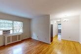 Located at 22 Manchester Place in Silver Spring, MD, this 2-bedroom, 1-bathroom residence offers a thoughtfully organized single-floor layout. Warm hardwood floors extend throughout every room, lending a cohesive and inviting character to the entire space.

The combined living and dining area forms the heart of the home, illuminated by natural light and anchored by an elegant chandelier overhead. A partial wall provides a subtle division between the living space and the kitchen, which features a stainless steel refrigerator and efficient use of the available space.

Both bedrooms are comfortably proportioned, each featuring hardwood floors, large windows with views of surrounding greenery, and classic radiator heating units. The primary bedroom receives ample natural light and offers a tranquil atmosphere. Four closets distributed throughout the unit provide generous storage solutions.

The bathroom is finished with crisp white subway tile surrounding a full soaking tub with shower, complemented by cabinetry and a window that introduces natural ventilation. Neutral white walls throughout the home provide a clean, bright backdrop adaptable to a variety of interior styles. A connecting hallway ties all rooms together efficiently, contributing to a practical and comfortable flow across the entire residence.