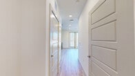 This well-appointed one-bedroom, one-bathroom unit offers a smart and efficient layout across a single floor. Light hardwood flooring flows throughout the main living areas, complemented by crisp white walls that create a bright, clean aesthetic. The open-concept living area is anchored by a ceiling fan and features large windows and glass double doors that invite generous natural light and outdoor views. The kitchen is outfitted with stainless steel appliances, including a French door refrigerator with ice maker and a range, alongside taupe cabinetry with brushed gold hardware and a subway tile backsplash. A dedicated hallway connects the main living spaces and includes access to the in-unit laundry area for added convenience. The bedroom is a comfortable retreat with dual windows overlooking greenery and hardwood flooring that transitions to plush carpeting. The bathroom showcases a granite-topped vanity with taupe cabinetry, brushed nickel hardware, and a framed mirror, with an adjacent double-door closet offering ample storage. Recessed lighting and panel-style interior doors add to the unit's modern character throughout.