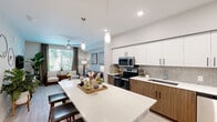 Located in Phoenix, Arizona, this well-appointed one-bedroom, one-bathroom residence offers a thoughtfully designed open-concept layout. The kitchen and living area flow seamlessly together, creating an inviting, multifunctional space ideal for both everyday living and entertaining. The kitchen is a standout feature, boasting two-tone cabinetry with white upper cabinets and warm wood-grain lower cabinets, a neutral tile backsplash, quartz countertops, a large center island with pendant lighting overhead, and a full suite of stainless steel appliances including a refrigerator with ice maker, electric range, microwave, and dishwasher. The living room is bright and airy, benefiting from a large window that frames lush outdoor greenery, a ceiling fan, and light wood-style flooring that continues throughout the home. The spacious primary bedroom accommodates a king-size bed comfortably, features its own ceiling fan, a generous window with outdoor views, and ample room for additional furnishings. The bathroom is clean and modern, with a wood-tone vanity, quartz countertop, a large mirror, and a walk-in shower. A hallway connects all areas efficiently, completing this cohesive and stylish single-floor home.
