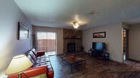 This single-floor residence offers a well-organized layout that balances communal living and private spaces. The living room serves as the centerpiece of the home, highlighted by a striking floor-to-ceiling stone corner fireplace with a wood mantle, dark hardwood-style flooring, and a sliding glass door that opens to a private outdoor balcony, allowing natural light to filter into the space. A textured ceiling and ceiling light fixture complete the room's character.

Adjacent to the living area, the dining room features wood-style flooring, a chandelier pendant light, built-in corner shelving, and a pass-through window connecting directly to the kitchen. The kitchen is equipped with dark cabinetry, light speckled countertops, and a double stainless steel sink.

The two bedrooms are carpeted and each offer a comfortable, functional layout. One bedroom includes a window with blinds that brings in natural light, while a hallway vanity area with a wood-framed mirror and built-in countertop provides additional grooming space outside the main bathroom.

The bathroom includes a full tub-shower combination, wood-style flooring, and a vanity with matching light countertops, rounding out this cohesive and practical living space.