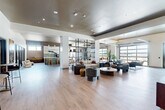 Located at 600 St Clair Ave SW in Huntsville, Alabama, this single-floor amenity space offers a generous and thoughtfully designed environment for socializing, recreation, and productivity. The open-plan layout is anchored by wide-plank hardwood-style flooring, dark coffered ceilings with recessed lighting, and dramatic glass garage doors that flood the interior with natural light while offering views to the outdoors.

The main lounge area features an expansive seating arrangement with contemporary curved furniture, round coffee tables, and curated décor, creating a welcoming gathering space. Adjacent to the lounge is a stylish bar and kitchen island clad in green tile, topped with white countertops and backed by a striking full-height marble slab — ideal for casual entertaining or community events. Bar seating and dining tables nearby accommodate a variety of social settings.

A dedicated golf simulator room, enclosed with glass partitions, houses a TruGolf system with artificial turf and a full projection screen. A separate game room offers a poker table, projector, and curated wall art. The conference room provides a polished setting with a large boardroom-style table, ergonomic seating, textured wall panels, and natural light from clerestory windows. The overall ambiance is modern, sophisticated, and highly functional.