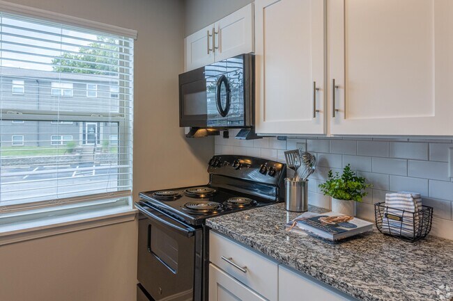 Cocina con encimeras de granito y electrodomésticos negros. - Union at JTown