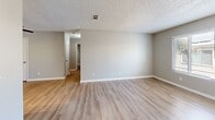 Located at 2130 N Marks Ave in Fresno, CA, this single-story 2-bedroom, 1-bathroom unit offers a practical and well-organized layout. Light wood-look flooring runs throughout the space, complemented by neutral gray walls and white trim, creating a clean and cohesive aesthetic. Textured ceilings add a classic residential touch visible across all rooms.

The galley-style kitchen is efficiently designed with white cabinetry lining both sides, warm-toned countertops, a double basin sink, stainless steel appliances including a refrigerator and range, and overhead track lighting that brightens the workspace. A pass-through opening connects the kitchen to the adjacent living area, which provides an open, airy feel with ample room to arrange seating and entertaining areas.

Both bedrooms are well-proportioned, with the primary bedroom offering a comfortable footprint. Each bedroom features windows fitted with horizontal blinds, allowing for natural light and privacy control. A dedicated closet provides convenient storage.

The bathroom includes a full-size soaking tub with a shower, a chrome fixtures, and clean white surrounds. The single-floor layout ensures easy accessibility throughout, making this a functional and straightforward space suited for everyday living in west Fresno.